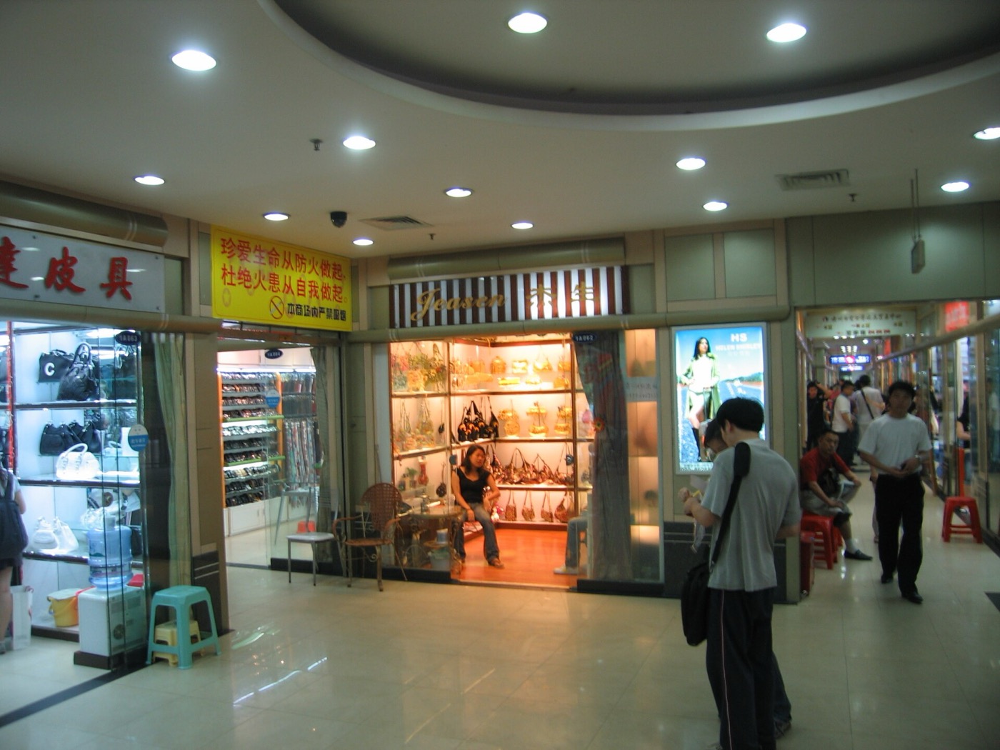 Inside a leather goods wholesale market in Guangzhou, with bags displayed in shop windows along a corridor